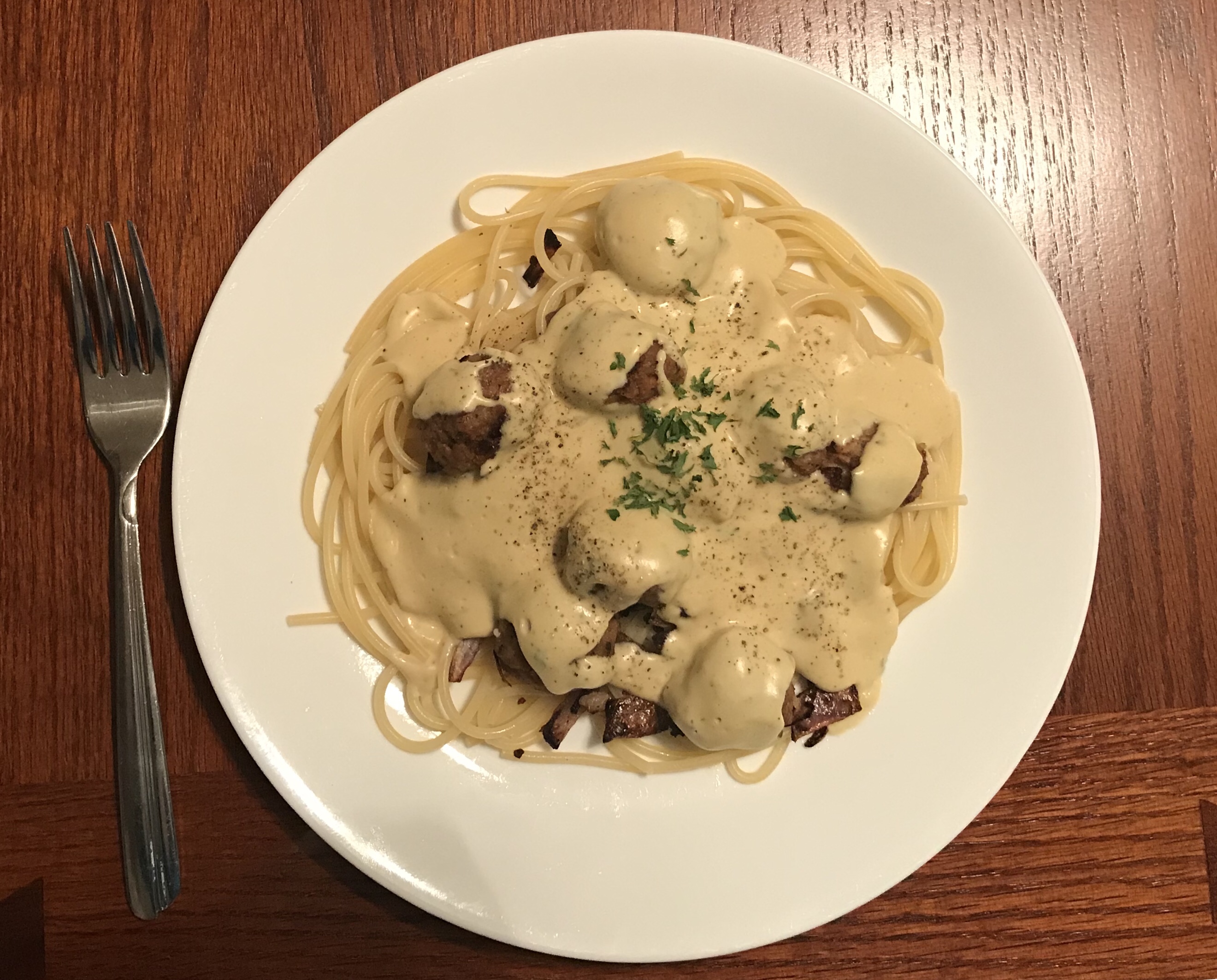 plate with pasta and vegan meatballs topped with vegan alfredo sauce