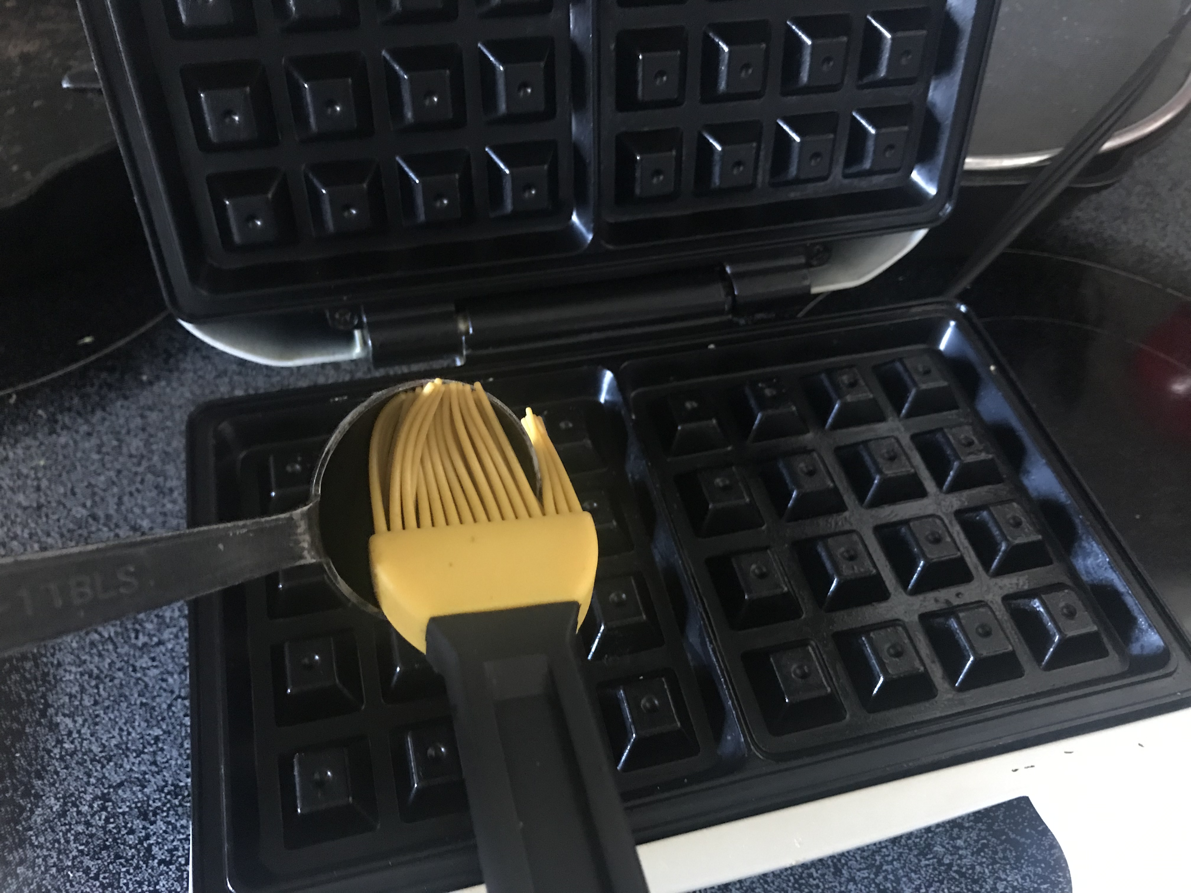 oiling the waffle iron with oil from measuring spoon